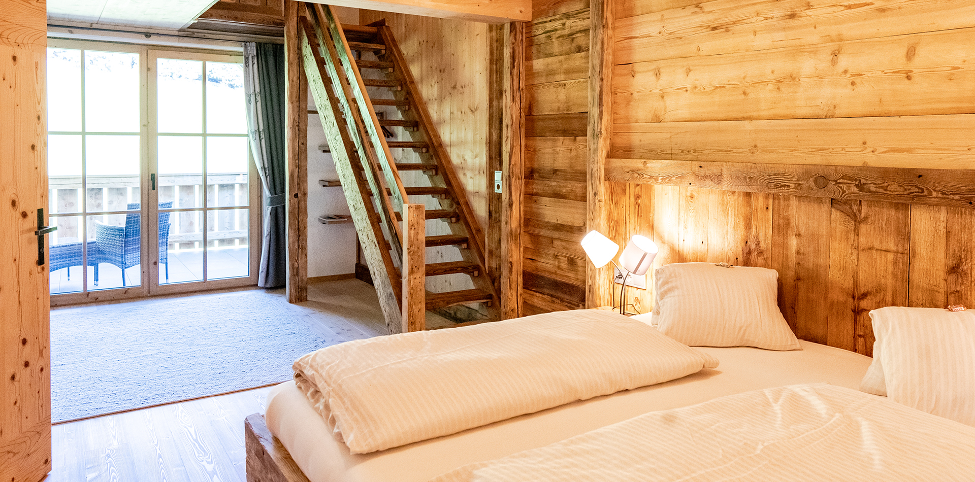 berggasthof-steckholzer-familienzimmer-doppelbett-mit-blick-auf-balkon-und-treppenaufgang